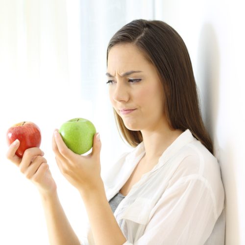 Woman deciding between red and green apples